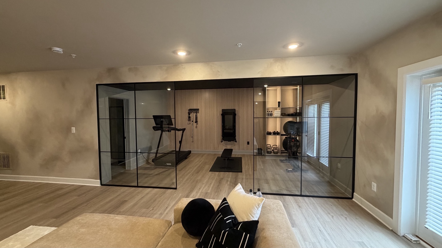 Large black framed glass wall enclosing a finished home gym