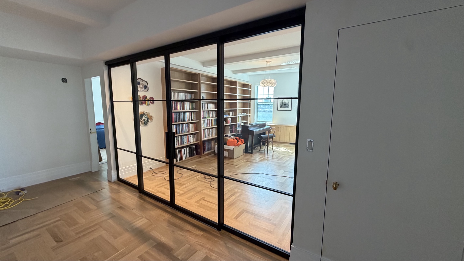 Four-panel sliding glass room divider beside a home library