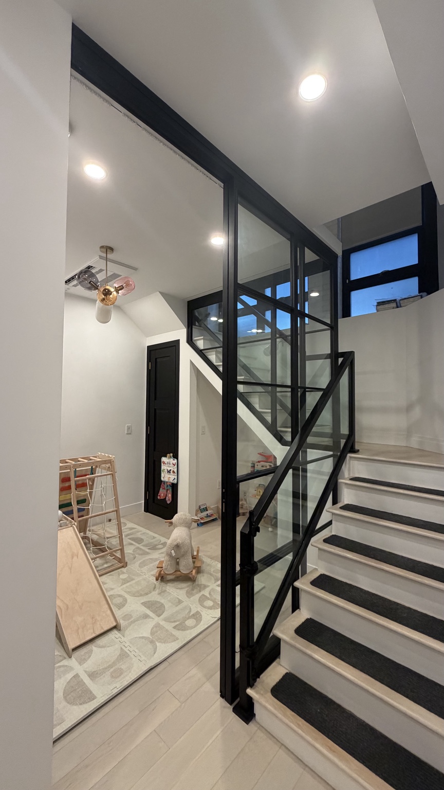 Black framed interior glass wall beside a staircase